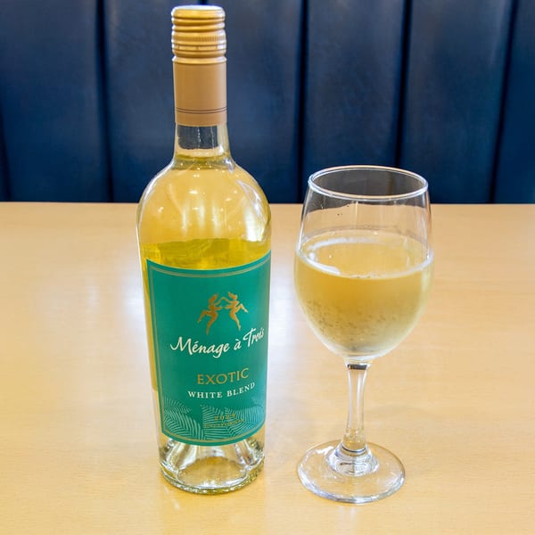 A bottle of Ménage à Trois Exotic White Blend wine and a glass of white wine.