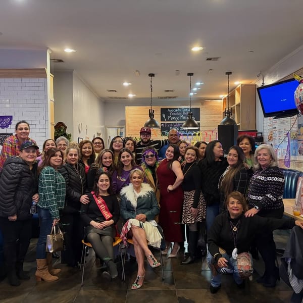 A large group of women and a few men pose for a photo inside a brightly lit restaurant.