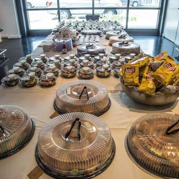 Buffet table displays covered cakes, assorted desserts, salads, and bowls of Lay’s chips in a bright restaurant.